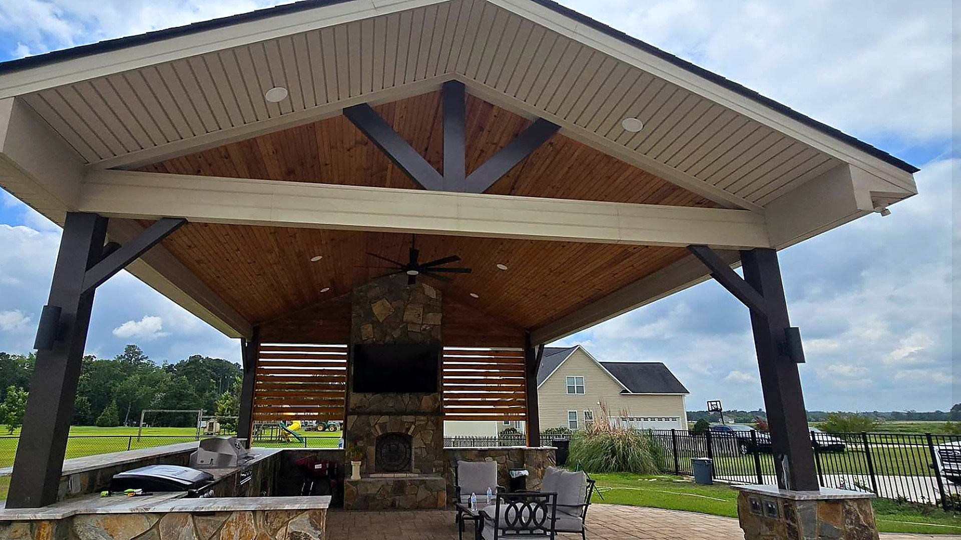 Finished backyard pavilion with cedar tongue-and-groove ceiling, stone outdoor kitchen and fireplace built in Vanceboro, NC